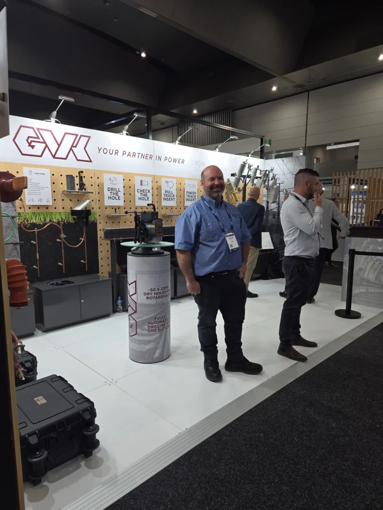 The G.V. Kinsman stand at AusRAIL PLUS 2025, showing earthing displays, a rail drilling unit and a team member beside it.